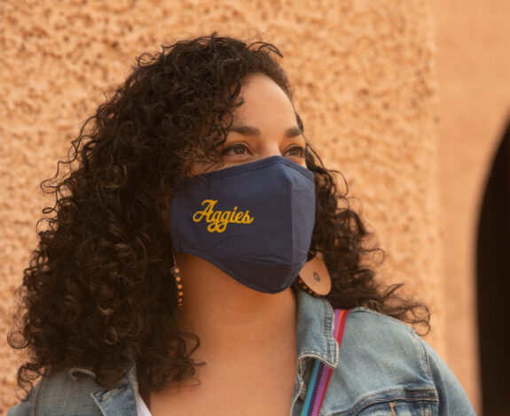 A woman wears an Aggies mask.